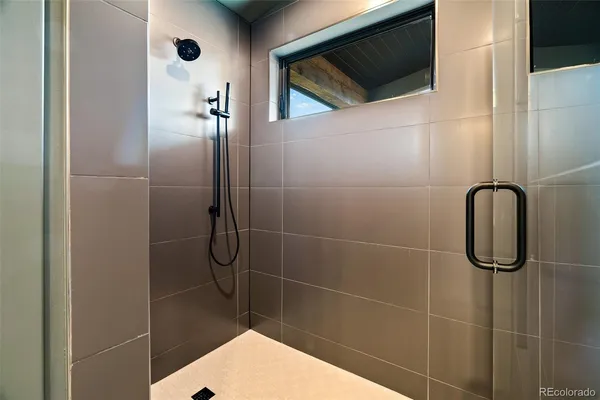 a bathroom with a shower and a tiled wall