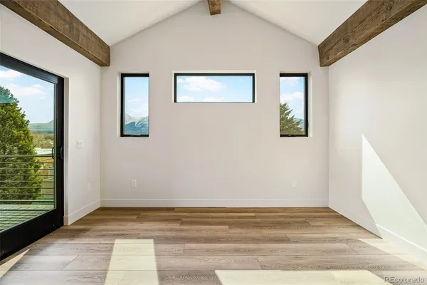 a view of an empty room with window and wooden floor