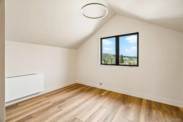 an empty room with wooden floor cabinet and windows