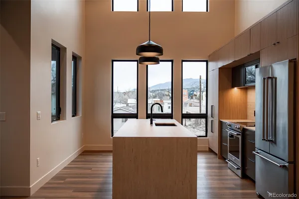 a kitchen with stainless steel appliances granite countertop a refrigerator a stove and a sink with wooden floor