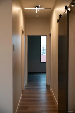 a view of a hallway with wooden floor and a bathroom