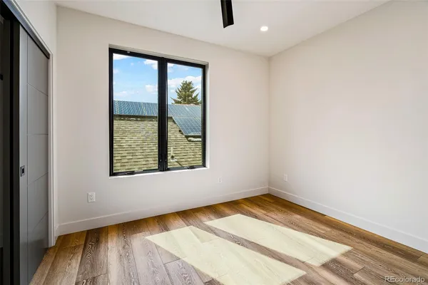 an empty room with wooden floor and windows