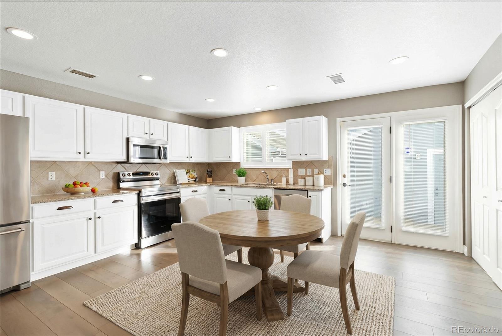 5796 Biscay Street Denver, CO 80249 - Photo 14 of 42 a kitchen with a dining table chairs and wooden floor