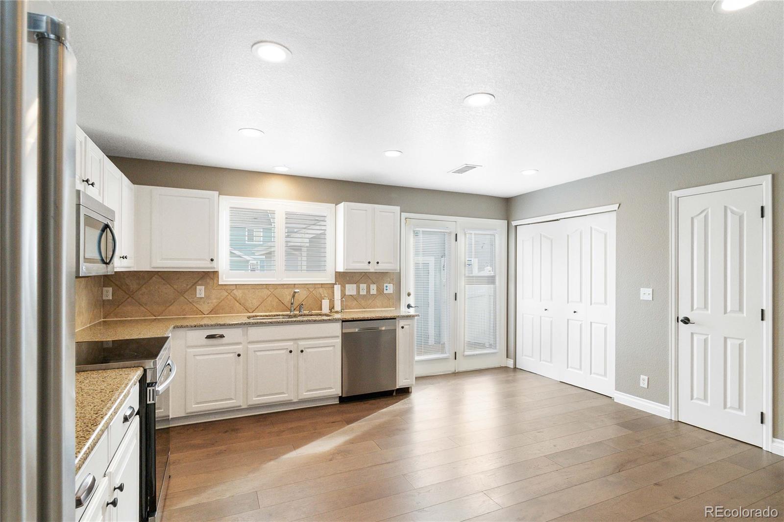 5796 Biscay Street Denver, CO 80249 - Photo 15 of 42 a view of a kitchen with a sink and dishwasher a oven with wooden floor