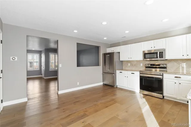 a kitchen with granite countertop a refrigerator and a stove top oven