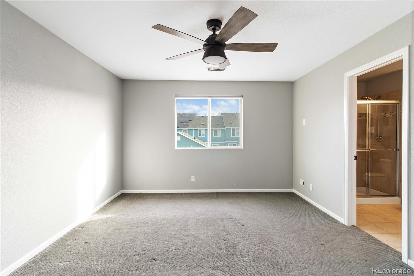 5796 Biscay Street Denver, CO 80249 - Photo 22 of 42 an empty room with a ceiling fan and windows