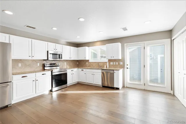 a large kitchen with stainless steel appliances and white cabinets