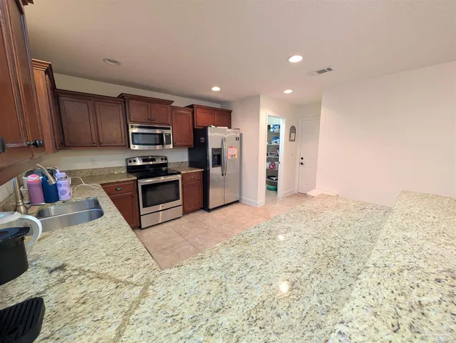 a kitchen with stainless steel appliances granite countertop a refrigerator sink and stove