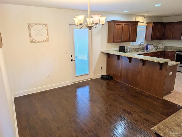 a kitchen with stainless steel appliances granite countertop a sink a stove top oven a refrigerator with wooden floors and cabinets