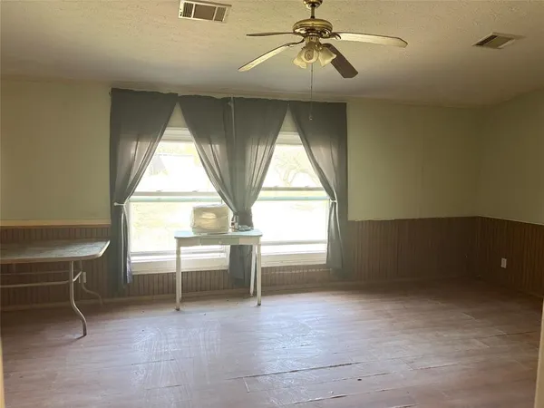 an empty room with windows and ceiling fan