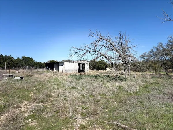 a view of a dry yard with wooden fence