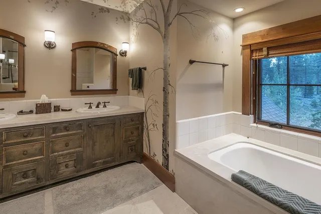 a bathroom with a tub a sink and a large mirror