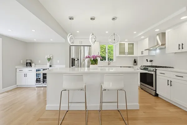 a kitchen with stainless steel appliances kitchen island granite countertop a stove a sink a refrigerator and white cabinets with wooden floor