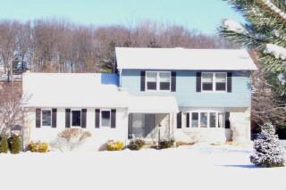 a front view of a house with a yard covered in snow
