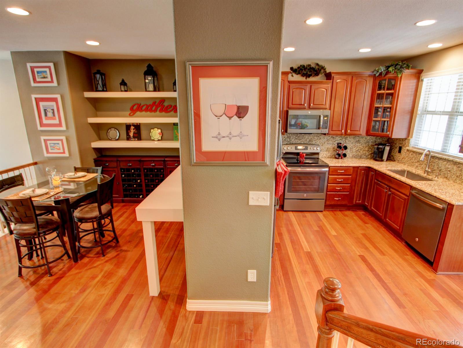 10186 RidgeGate Circle Lone Tree, CO 80124 - Photo 11 of 24 a kitchen with stainless steel appliances granite countertop a refrigerator a stove top oven and a dining table with wooden floor