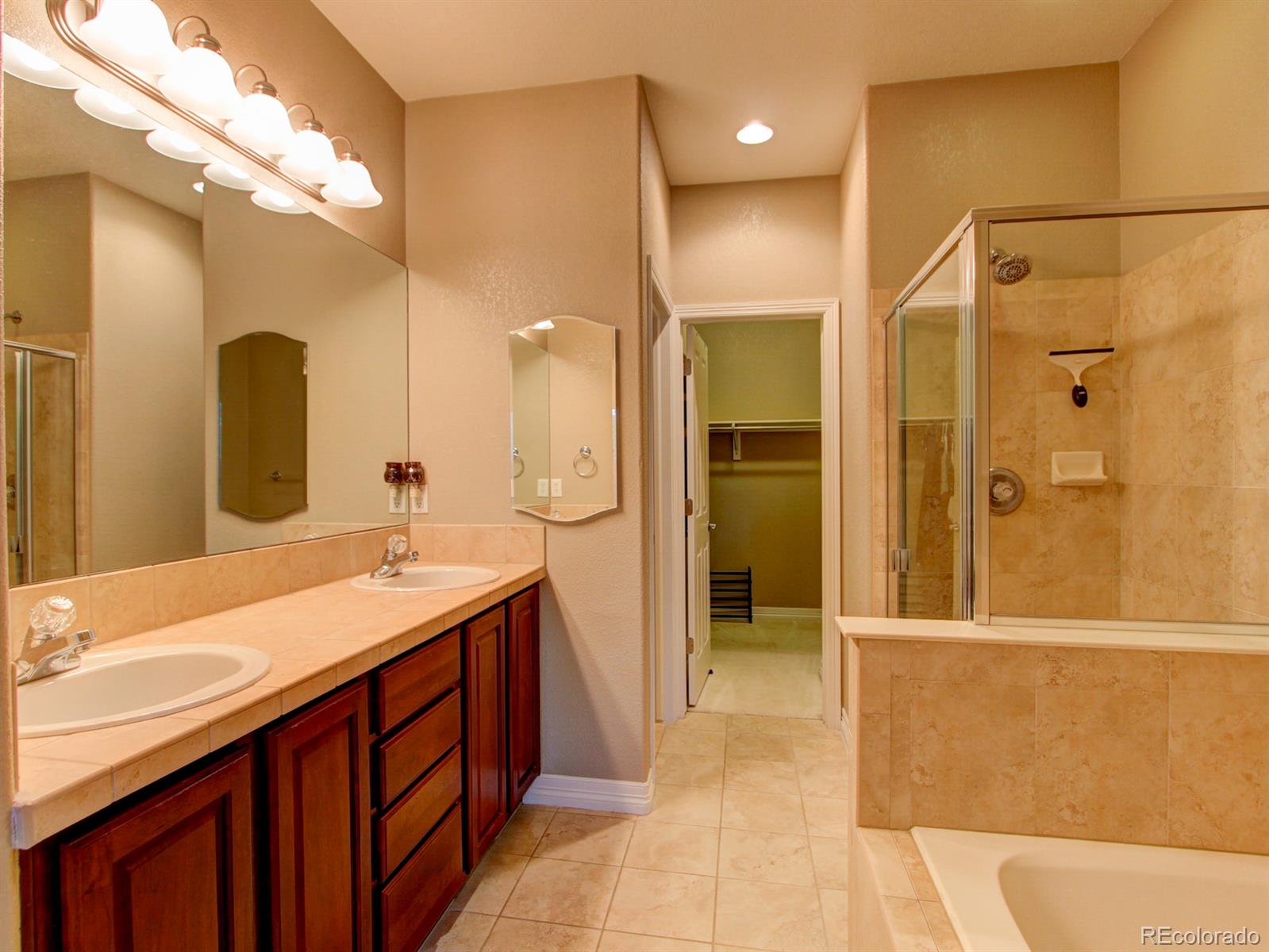 10186 RidgeGate Circle Lone Tree, CO 80124 - Photo 15 of 24 a bathroom with a granite countertop sink a toilet a mirror and shower