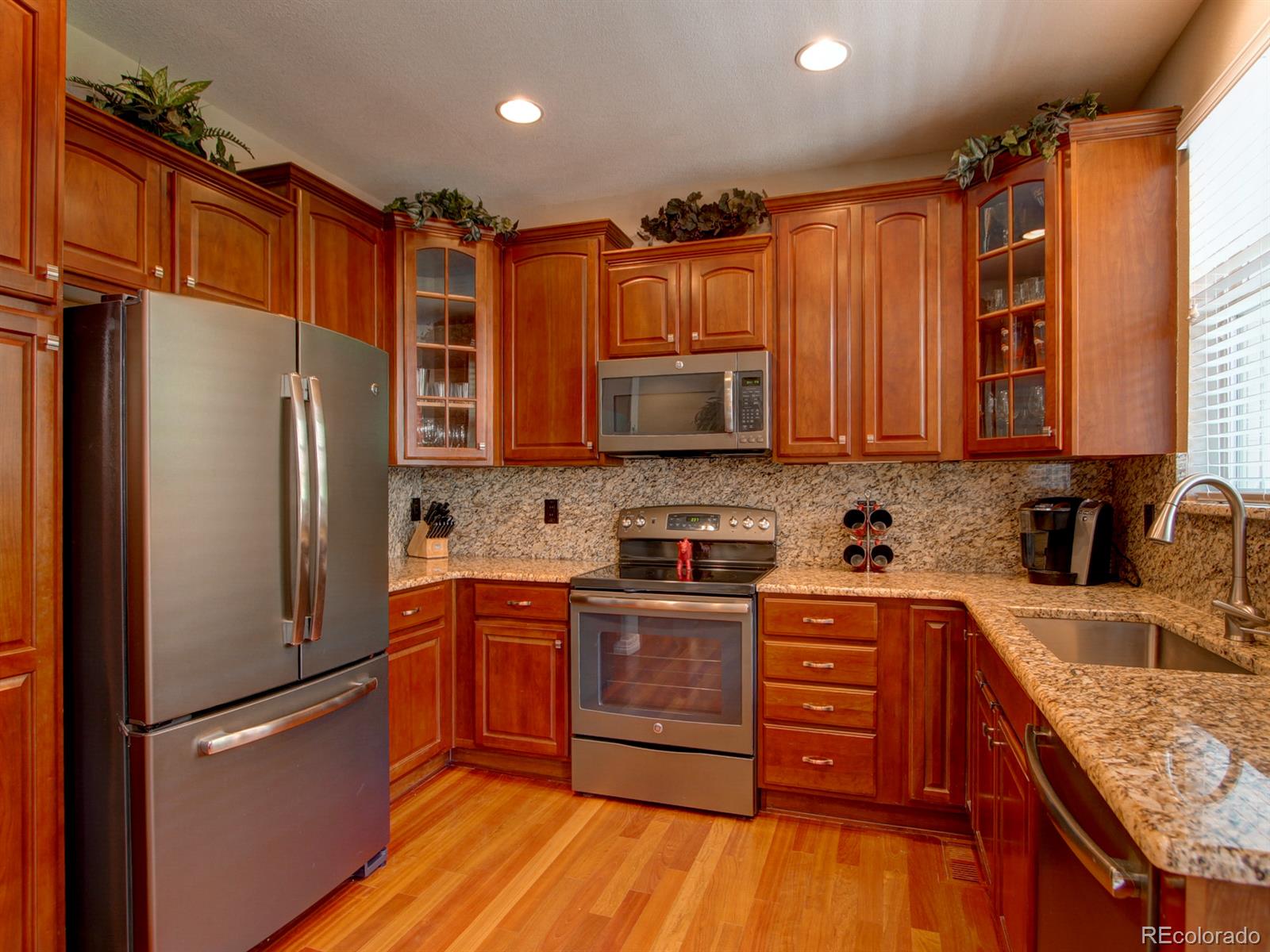 10186 RidgeGate Circle Lone Tree, CO 80124 - Photo 9 of 24 a kitchen with stainless steel appliances granite countertop a refrigerator oven a sink dishwasher and wooden cabinets with wooden floor