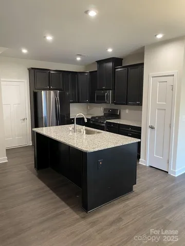 a kitchen with kitchen island granite countertop a sink and a refrigerator
