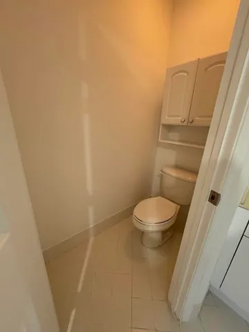 a white toilet sitting next to a small white wall
