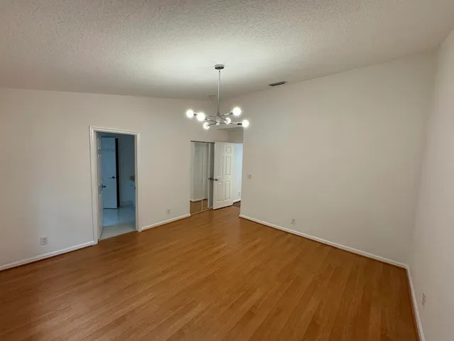 a view of an empty room with wooden floor and a chandelier