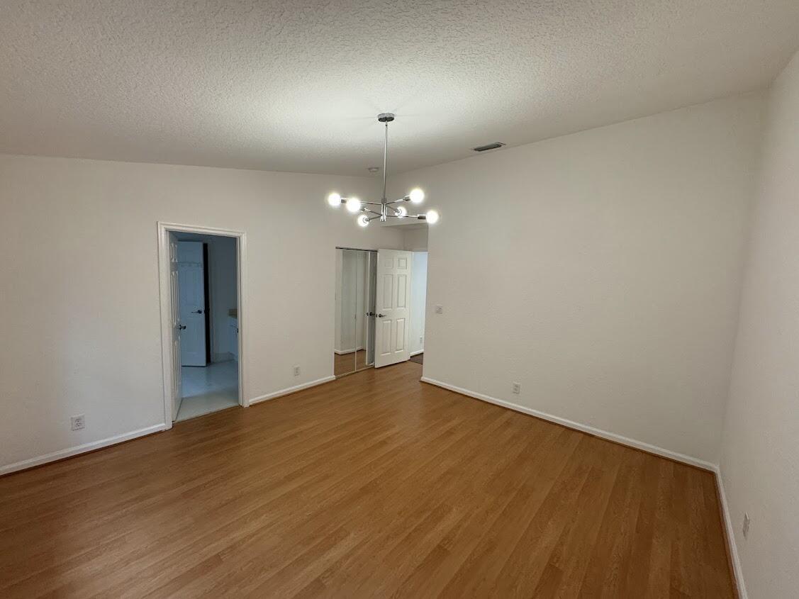 18237 Boca Way Drive Boca Raton, FL 33498 - Photo 20 of 36 a view of an empty room with wooden floor and a chandelier