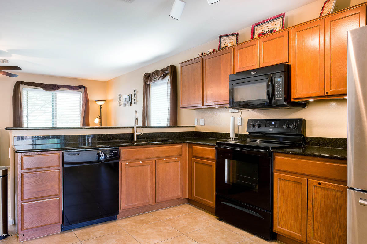 2676 South De Soto Road Apache Junction, AZ 85119 - Photo 4 of 19 a kitchen with stainless steel appliances granite countertop a stove a sink and a microwave