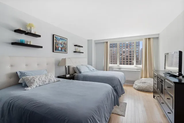 a bedroom with two beds and a flat tv screen on dresser