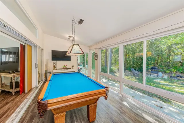 a room with pool table flat screen tv and windows