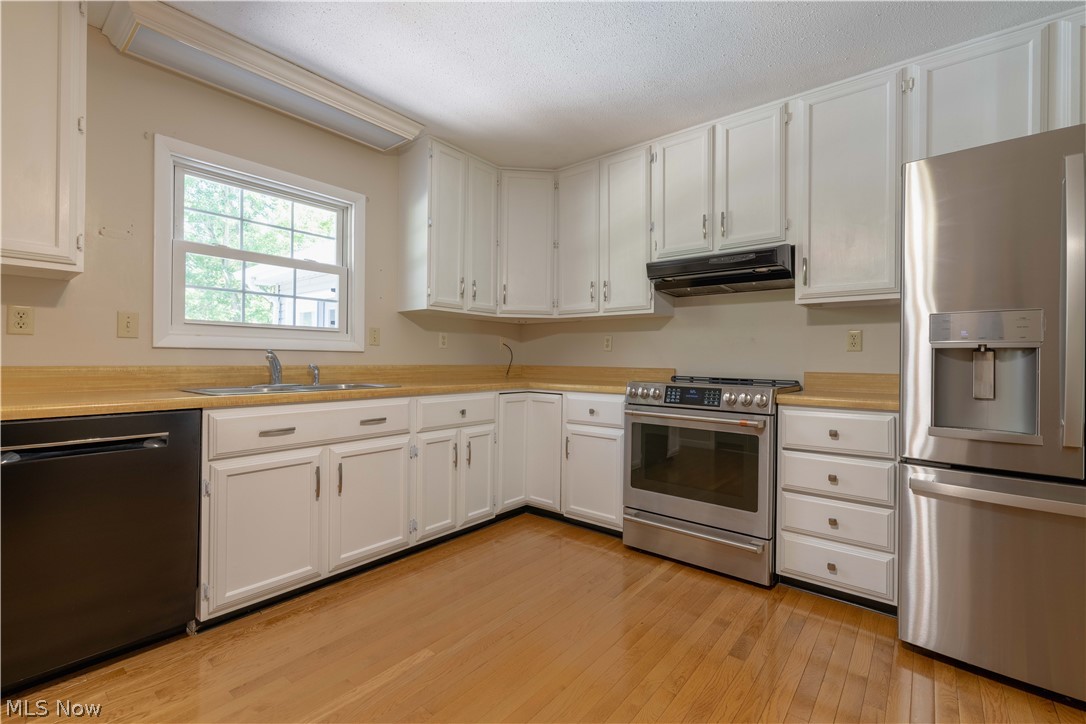 3963 Mark Road Cambridge, OH 43725 - Photo 13 of 50 Kitchen with stainless steel appliances, white cabinetry, fume extractor, light wood-type flooring, and sink