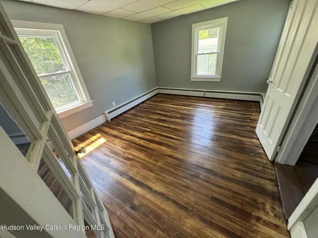 a view of an empty room with wooden floor and a window