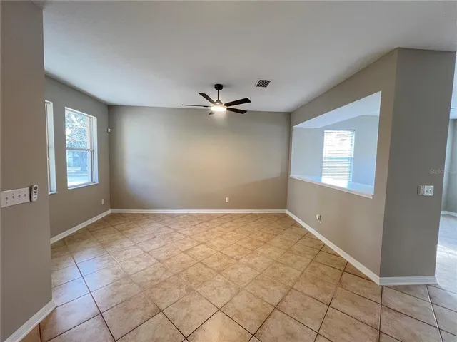 an empty room with windows and ceiling fan