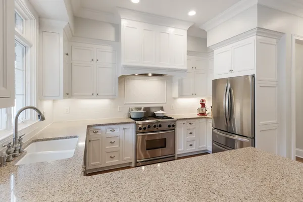 a kitchen with stainless steel appliances granite countertop a stove a refrigerator and a sink with wooden cabinets