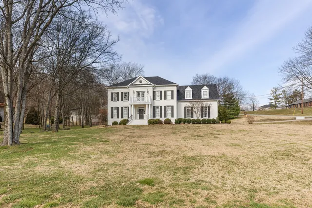 a view of a big house with a big yard and large trees