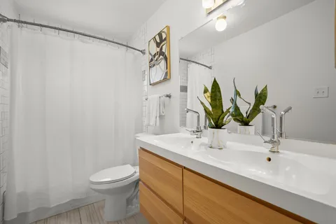 a bathroom with double vanity sink a toilet and a mirror