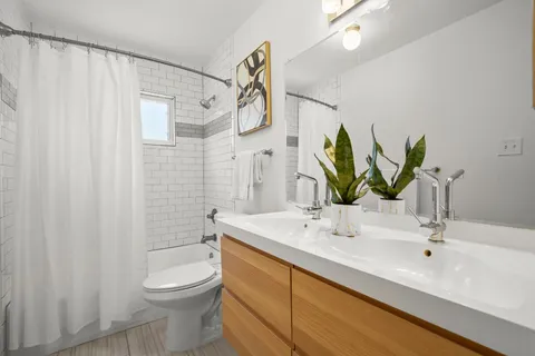 a bathroom with double vanity sink a toilet and a shower
