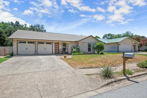 a view of a house with a yard and large tree
