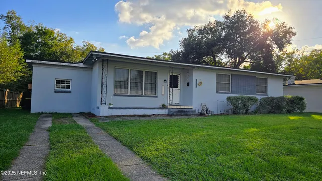 a backyard of a house with potted plants and a large tree
