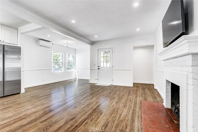 a view of an empty room with wooden floor and a fireplace