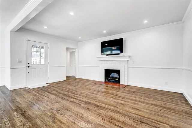 a view of empty room with wooden floor and fireplace