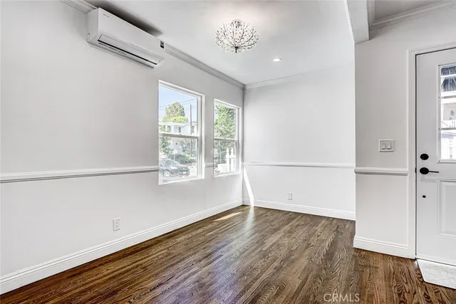 an empty room with wooden floor cabinet and windows