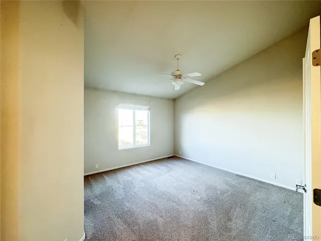 an empty room with a ceiling fan and a window