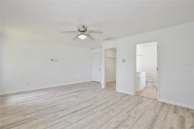 an empty room with wooden floor and ceiling fan