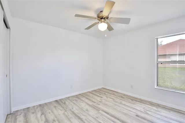 an empty room with a window and ceiling fan