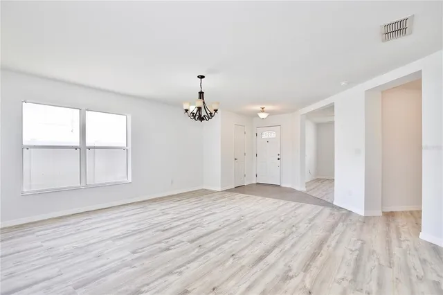 an empty room with wooden floor cabinet and windows