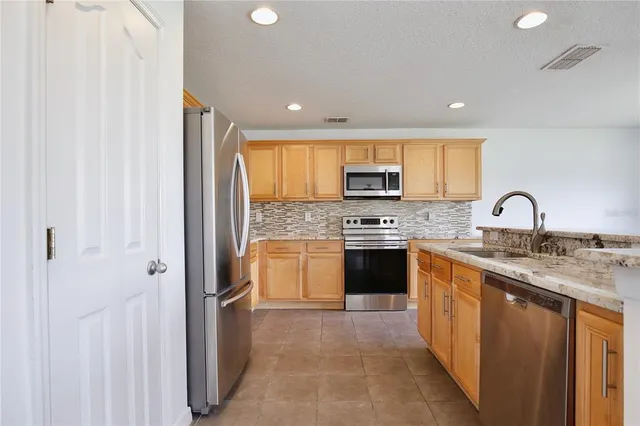 a kitchen with stainless steel appliances granite countertop a stove a sink and a refrigerator
