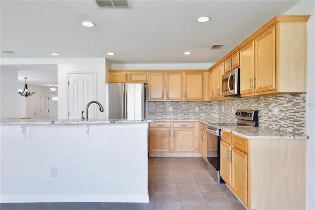 a kitchen with stainless steel appliances granite countertop a stove a sink a refrigerator and white cabinets with wooden floor