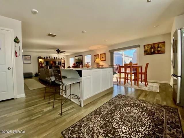a living room with furniture and a dining table with wooden floor