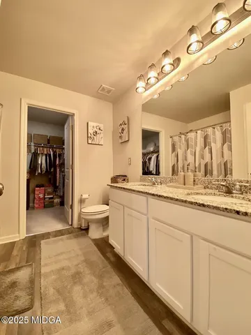 a spacious bathroom with a granite countertop sink mirror and a toilet