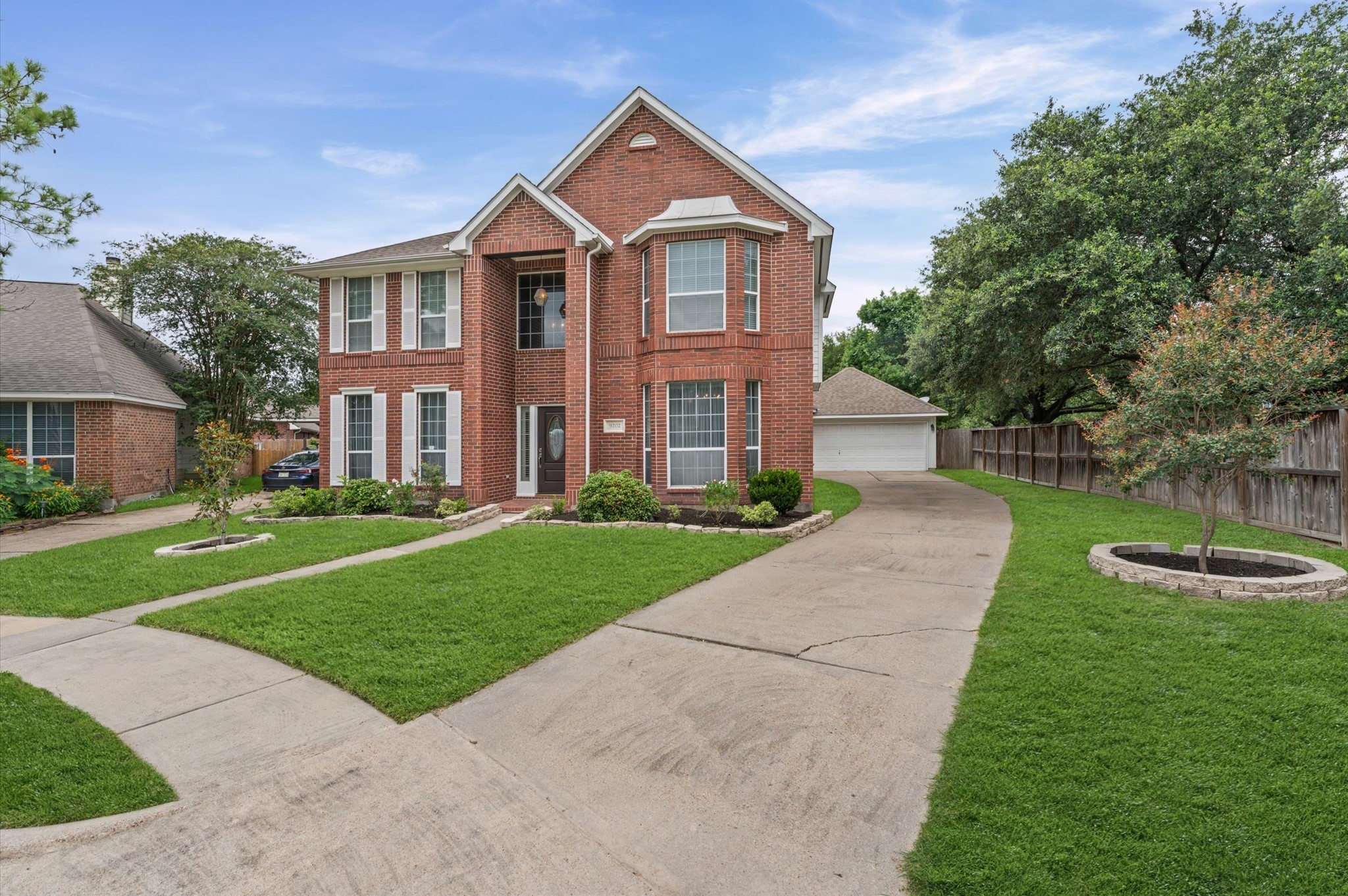 9202 State Walk Circle Houston, TX 77064 - Photo 2 of 25 This is a charming two-story brick home with a classic design, featuring a well-maintained front lawn, a spacious driveway leading to a detached garage, and mature trees for added privacy and shade.