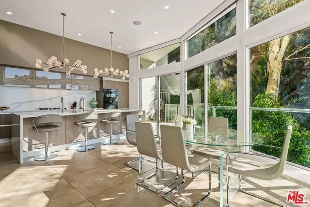 a view of a patio with couches table and chairs under an umbrella with a small garden